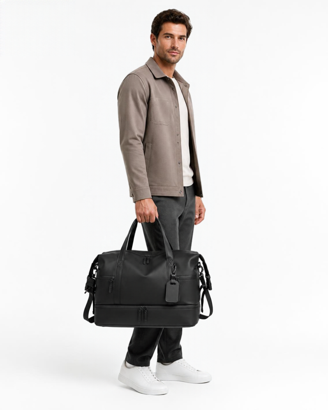 Man holding the black AVREN men's travel duffle bag with vegan leather finish, multiple zippered pockets and a dedicated shoe compartment, styled with a smart casual outfit against a white studio background.